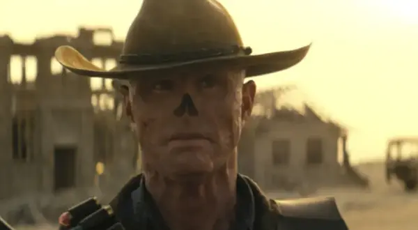 Ghoul z Fallout, w kapeluszu kowbojskim, z bliznami na twarzy, przemierza pustkowia.