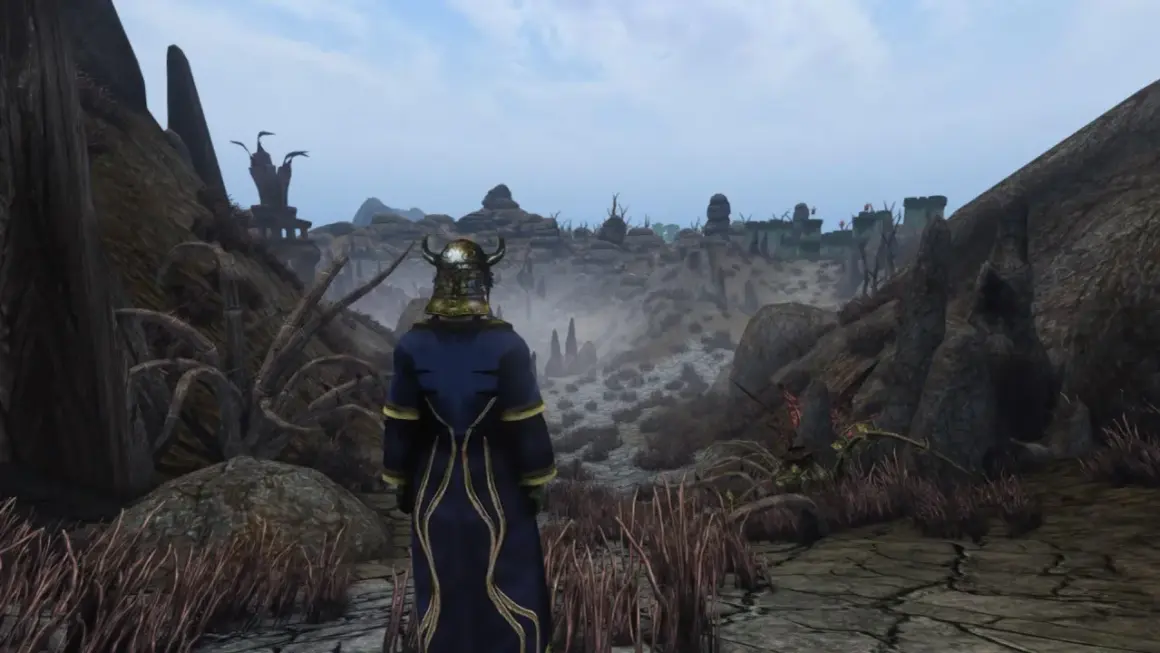 Postać w zbroi i niebieskim płaszczu patrzy na pustynny krajobraz z ruinami w oddali. To Morrowind Remastered.